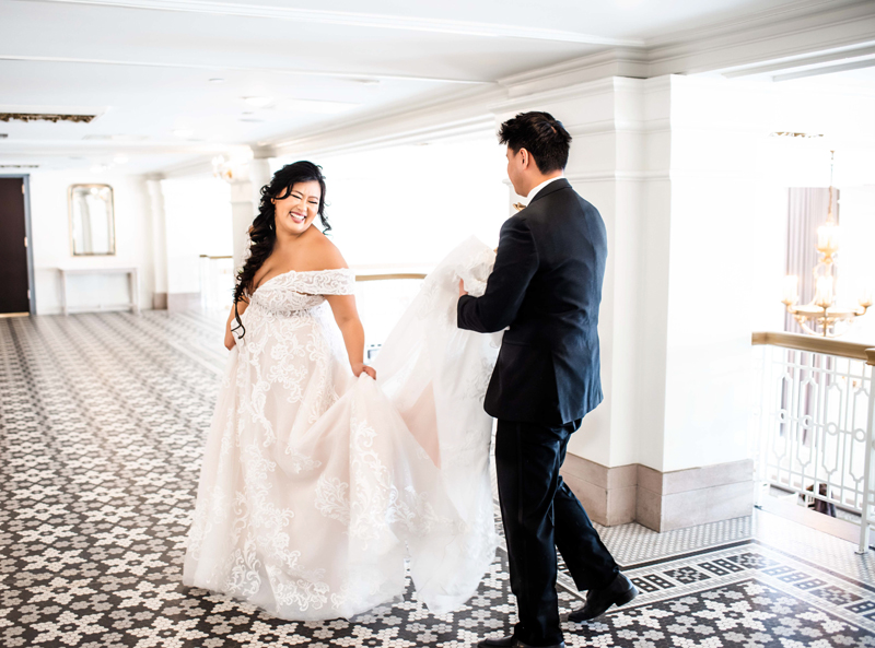 wedding photography, bride smiling at groom, groom holding train of dress